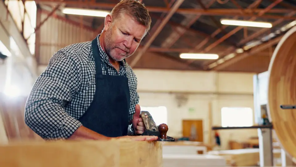 A man in his fifties working at a wood workshop bench