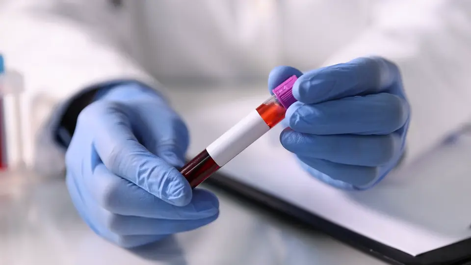 A lab technician holding a blood sample tube